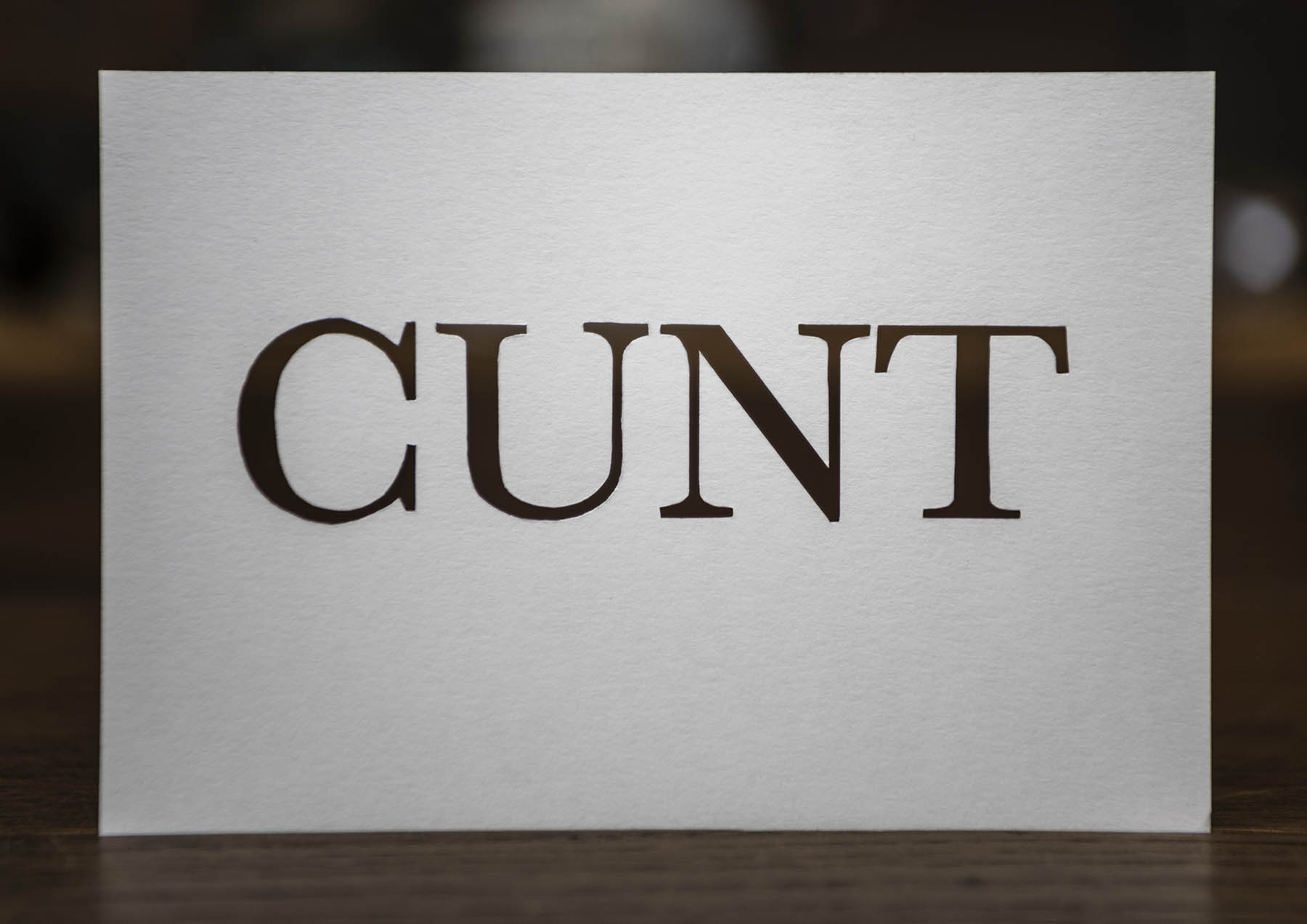 Cunt cut out of white card with a white background