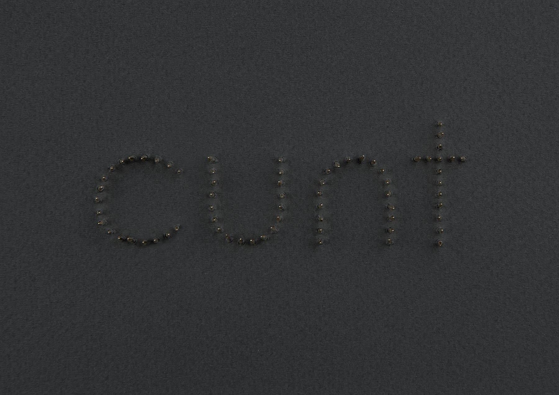 Brass tacks on grey card spell cunt