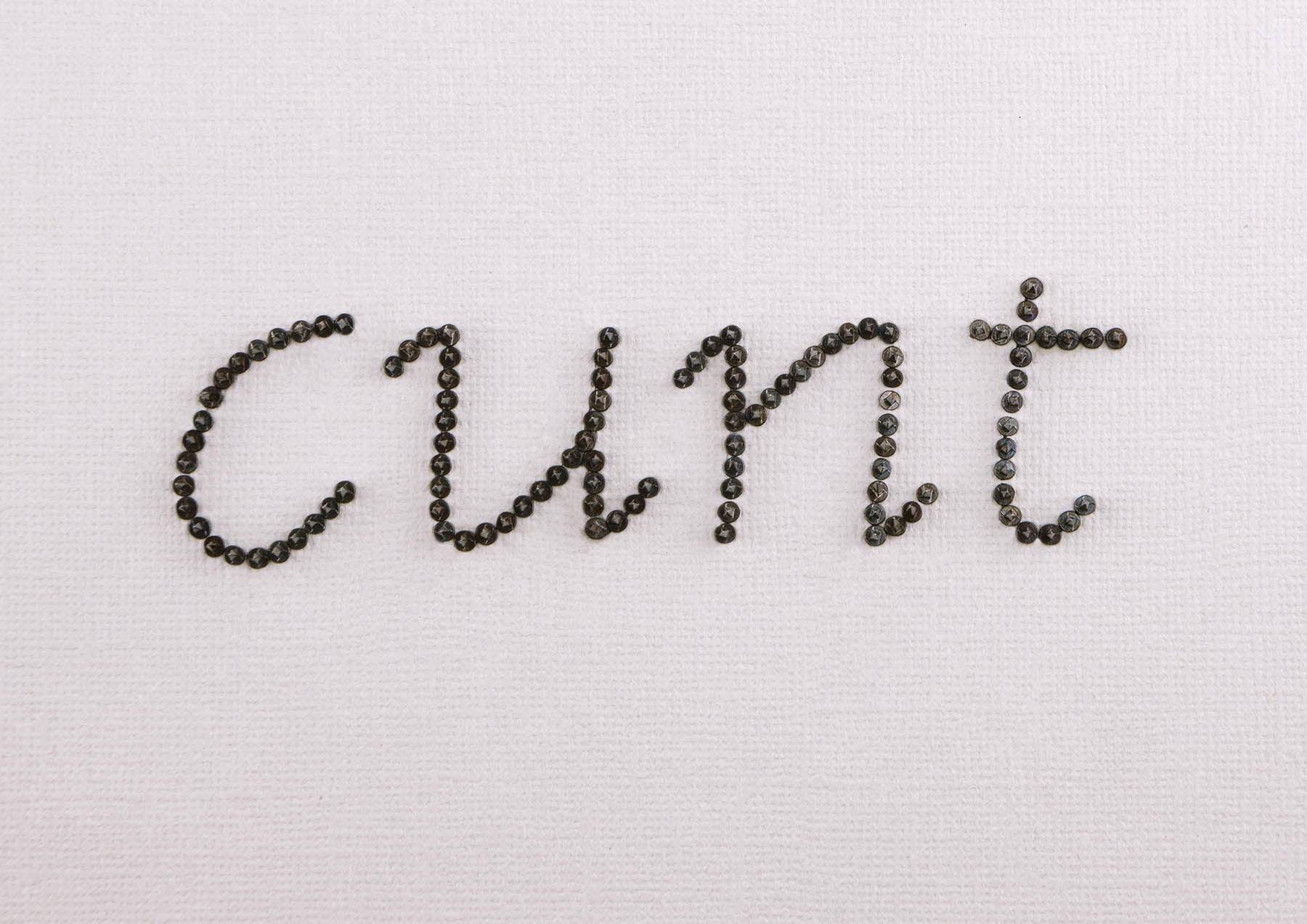 Cunt made from black tacks on off white paper