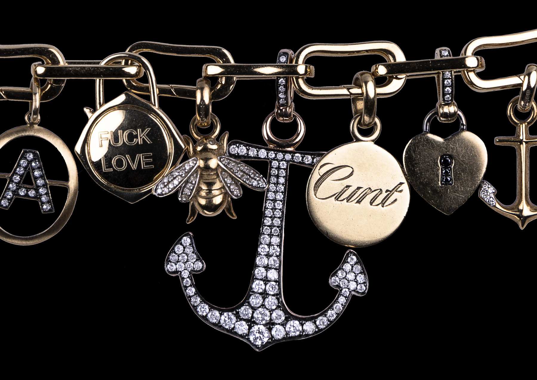 Cunt engraved on gold disc on charm bracelet